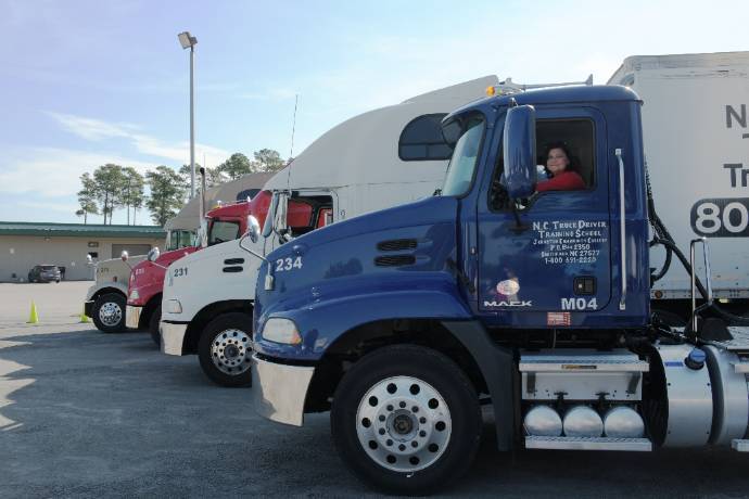 Image of a blue 18 wheeler with a women driving it.
