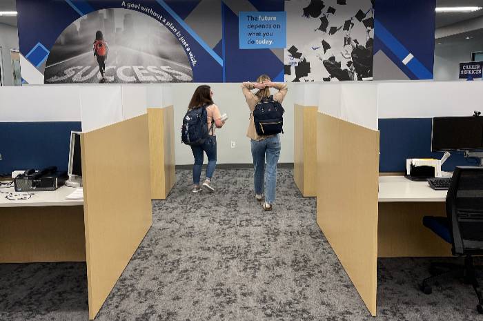 two students walking in between desks at student success center